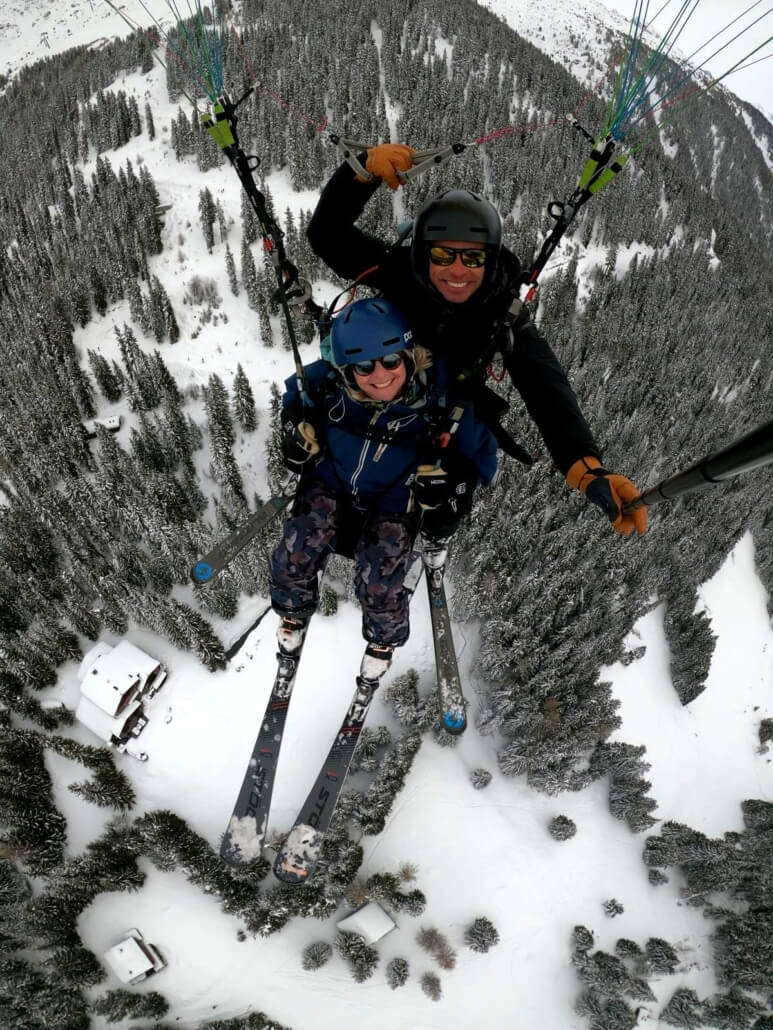 Paragliding in Verbier Switzerland aragliding above Verbier Switzerland with skier flying over snowy forest in the Swiss Alps