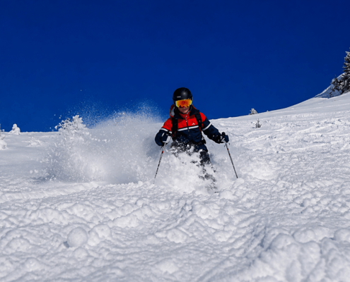 Skier skiing powder snow under a blue sky in Verbier Switzerland